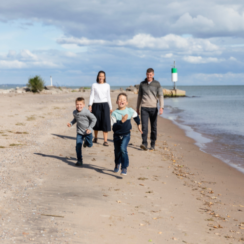 A family of four run along a sandy beach